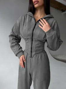 Dettaglio di una tuta grigia da donna con felpa con cappuccio e vita a corsetto chic.