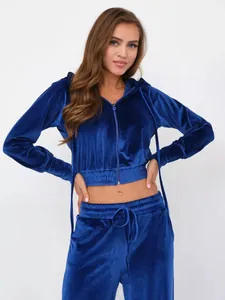 Nahaufnahme eines blauen Samt-Trainingsanzugs mit kurzem Kapuzenpullover und Kordelzughose.
