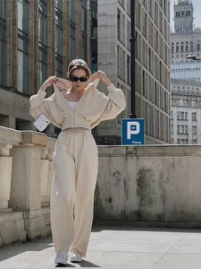 Women's cream zip-up hoodie and wide-leg sweatpants set in a city street setting