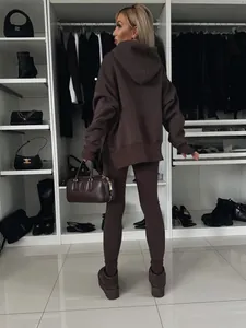 Vista posterior de una mujer con una sudadera con capucha oversize marrón chocolate y leggings a juego