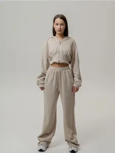Detail view of a beige zip-up hooded sweatshirt and matching wide-leg lounge pants