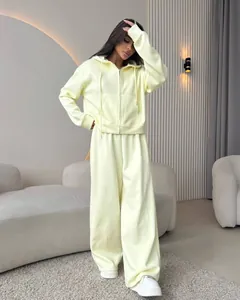 Full view of women's pale yellow zip-up hoodie and wide-leg tracksuit set in modern interior