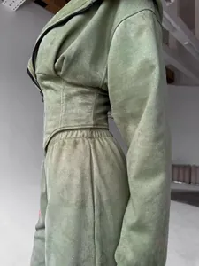 Primo piano di una tuta verde salvia in finto camoscio con dettaglio vita stile corsetto unico