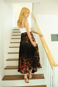 Full-length view of a women's floral print maxi skirt worn by a model on white stairs