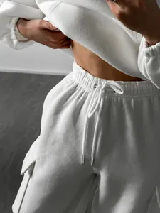 Close-up of white fleece tracksuit featuring elastic drawstring waist and cargo pockets.