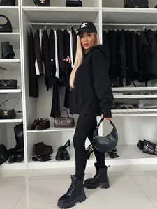 Foto de cuerpo entero de una modelo con un conjunto de sudadera negra oversize y leggings