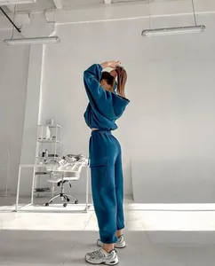 Teal blue women's fashion sport hoodie and sweatpants set in a minimalist studio