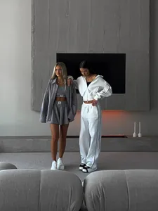 Deux femmes portant des ensembles de survêtement blancs et gris dans un salon moderne