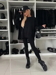 Mujer con una sudadera negra extragrande y leggings en un elegante vestidor de lujo