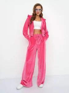 Detail des pinkfarbenen Samt-Trainingsanzugs mit Kapuzenjacke und weit geschnittener Hose