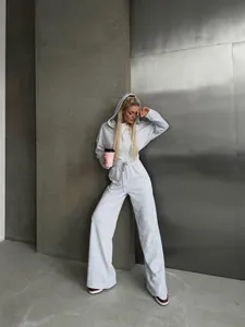 Casual grey zip-up hooded jumpsuit for women displayed in a modern industrial setting