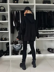 Vista trasera de un conjunto informal de sudadera con capucha negra y leggings en un armario.