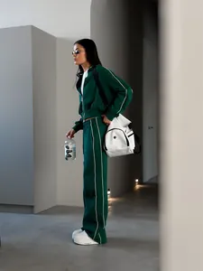 Vue d'une femme en survêtement de sport vert à rayures blanches et baskets à plateforme.