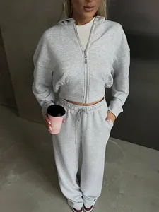 Detailed view of a woman wearing a gray two-piece tracksuit with cropped zip hoodie and pants