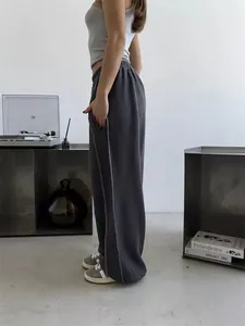 Side profile of loose gray street style sweatpants featuring white contrast stitch details