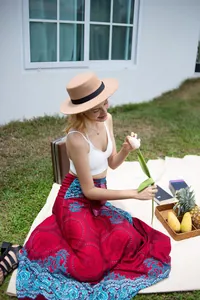 Woman wearing a vibrant bohemian printed red maxi skirt in a sunny outdoor picnic setting