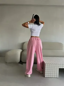 Rear view of women's loose pink sweatpants in a minimalist American street style setting