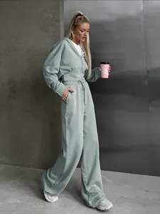 Lifestyle view of women's sage green two-piece hoodie and wide-leg jogger set.