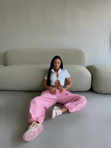 Woman posing in pink baggy sweatpants and white crop top for street style look