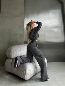 Model posing in a charcoal grey two-piece casual hooded set against industrial wall