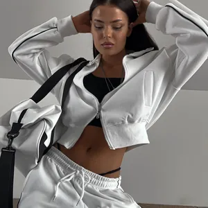 Ensemble de survêtement blanc deux pièces pour femme avec veste zippée et pantalon à cordon.