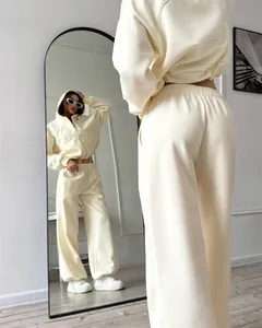 Gedetailleerd voor- en achteraanzicht van een crème zip-up hoodie en bijpassende broek set.