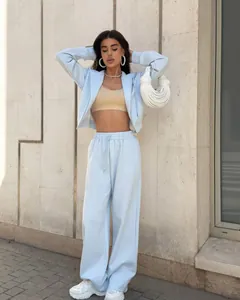 Modèle portant un ensemble sweat à capuche et jogging bleu clair devant un mur.