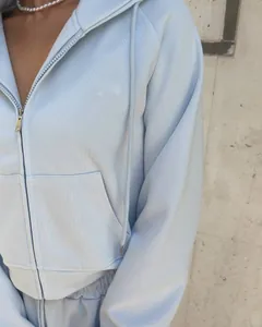Détail d'un sweat à capuche bleu clair avec fermeture éclair en métal et tissu doux.