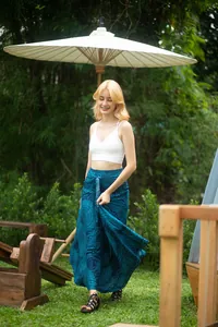 Model wearing a blue bohemian printed maxi skirt walking in a sunlit garden