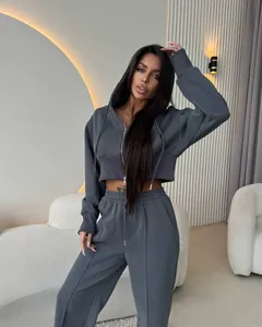 Vue complète d'une femme portant un ensemble de jogging gris avec sweat à capuche court.