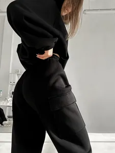 Detailed view of black cargo sweatpants with side pocket from a sporty hoodie set on a model.