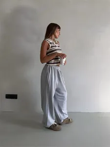 Street style shot of a woman in grey loose sweatpants and a striped polo top.