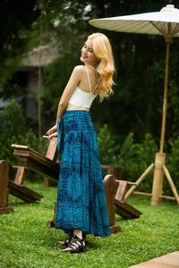 Detailed view of a woman wearing a blue floral print lace-up maxi beach skirt in a garden