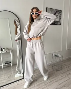 Volledig beeld van een vrouw in een grijs tweedelig trainingspak in een moderne kamer.
