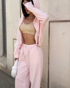 Vue complète d'un modèle portant un survêtement rose clair deux pièces avec veste et pantalon.