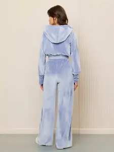 Rückansicht eines blauen Samt-Hoodies und einer weit geschnittenen Hose für Damen