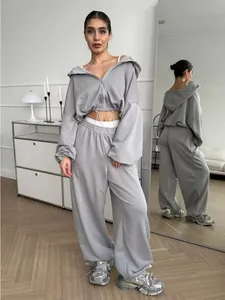 Full body view of a women's grey two-piece tracksuit featuring a cropped zip-up hoodie