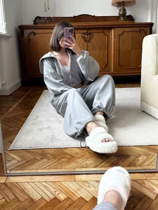 Model wearing a grey zip-up hoodie and matching joggers in a cozy home interior