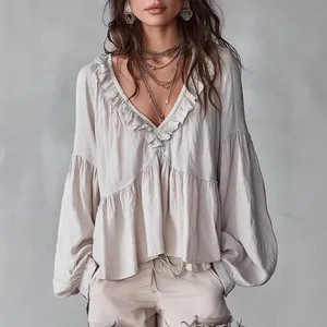 Detailed view of women's greige ruffled V-neck blouse with bohemian lantern sleeves.