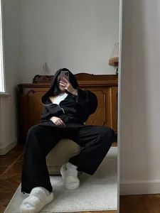 Mirror selfie of a woman in a black oversized zip-up hoodie and matching sweatpants set.