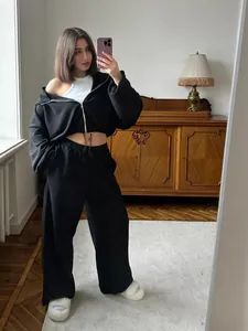 Full-length mirror selfie of woman in black two-piece cropped hoodie and sweatpants set.