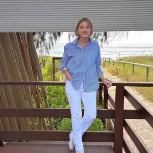 Asian model wearing a blue striped button-down shirt and white trousers at a beach resort