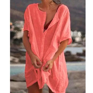 Close-up of a coral pink loose short-sleeved linen beach cover-up shirt for women