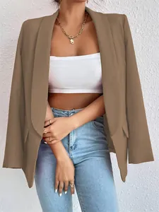 Detalle de un blazer marrón con solapa tipo chal, top blanco y collar dorado.