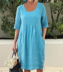 Model wearing a blue round neck loose-fit dress with side pockets in a garden setting