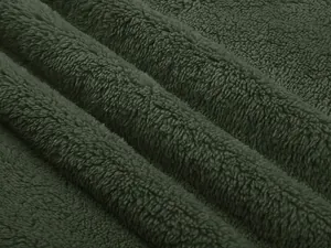 Dettaglio macro che mostra la morbida trama del tessuto in pile sherpa verde per giacca uomo