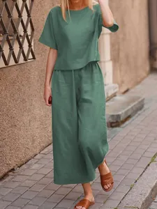 Full view of casual green linen two-piece set worn by model on outdoor sidewalk
