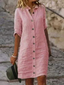 Detail of a pink linen-look shirt dress featuring vintage round buttons and a classic collar.
