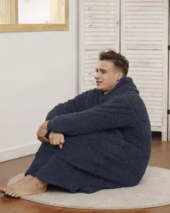 Male model wearing a navy blue oversized Sherpa hoodie blanket in a cozy room setting
