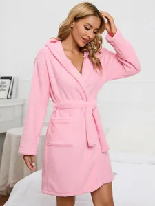 Woman wearing a cozy pink hooded fleece bathrobe with a soft tie belt and pockets.